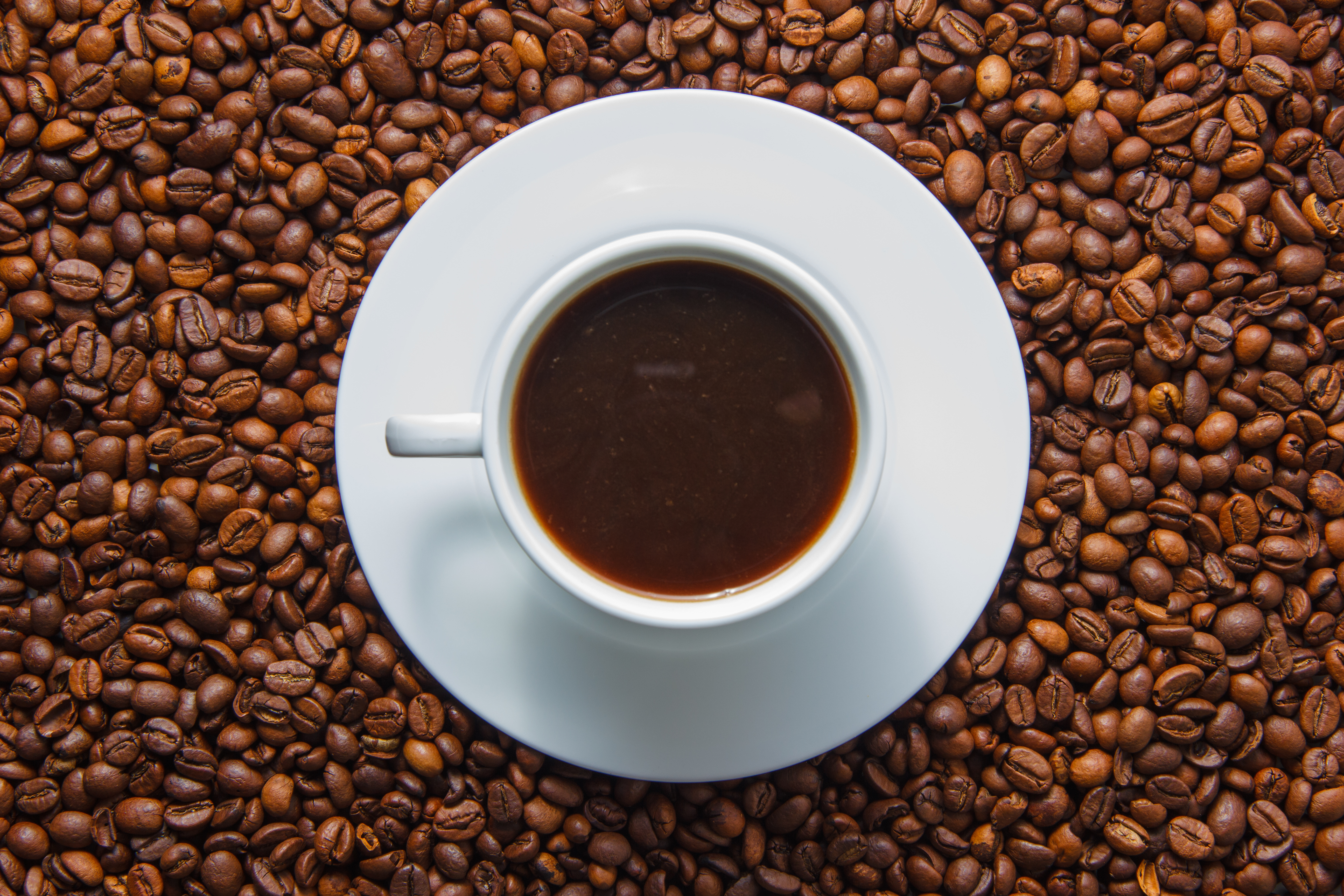 Xícara com café no interior disposta em cima de grãos de café